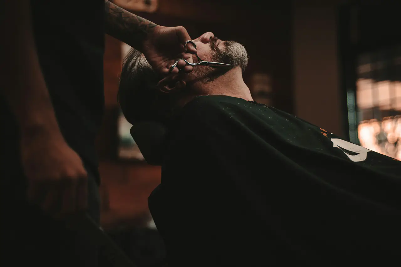 Client installé dans le fauteuil d'un barbier