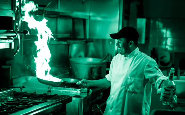 Chef faisant flamber une poêle en cuisine